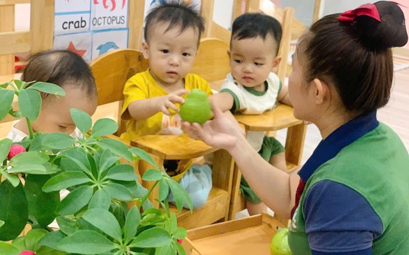Cô đưa quả cho các bé ở góc lớp có thẻ từ