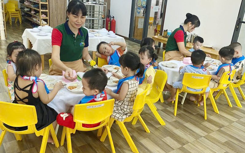 Cô và các bé ăn trưa ở bàn ăn của lớp