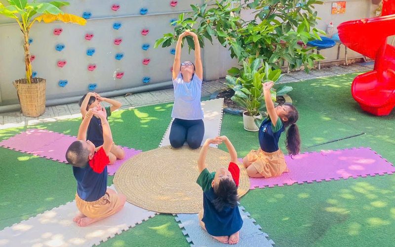 Cô và các bé tập vận động trên thảm ở sân chơi